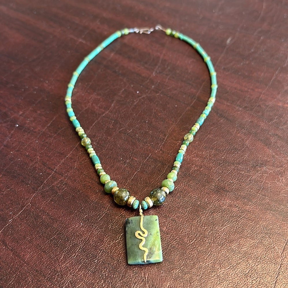 Necklace with green and gold beads and a green onyx charm with Gold accents.
